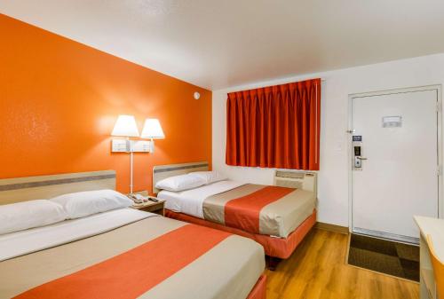 una camera d'albergo con due letti e pareti arancioni di Motel 6-Schiller Park, IL - Chicago O'Hare a Schiller Park