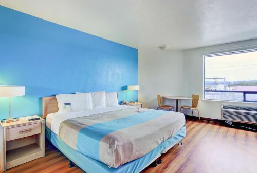 a bedroom with a large bed with a blue wall at Motel 6-Coos Bay, OR in Coos Bay