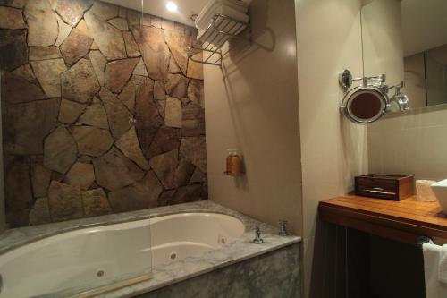a bathroom with a tub and a stone wall at Mine Hotel in Buenos Aires
