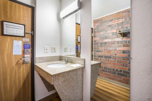 Motel 6-Madison, WI - East في ماديسون: حمام مع حوض وجدار من الطوب