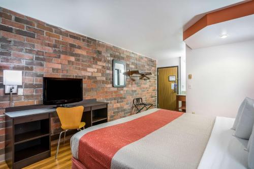 a bedroom with a bed and a desk with a television at Motel 6-Madison, WI - East in Madison