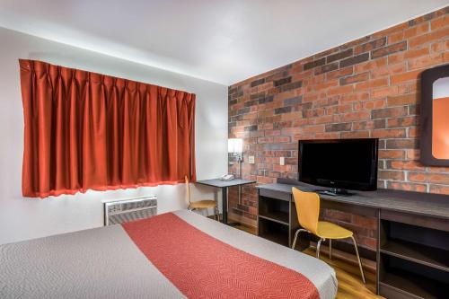a hotel room with a bed and a desk with a television at Motel 6-Madison, WI - East in Madison