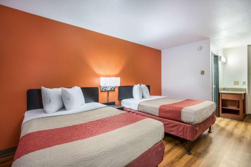 a hotel room with two beds with orange walls at Motel 6-Madison, WI - East in Madison