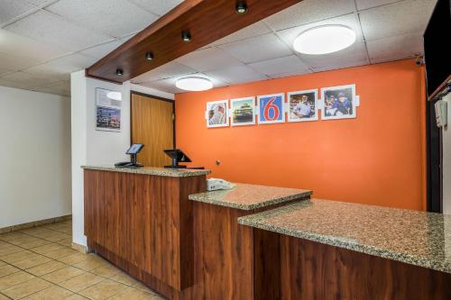 an office with an orange wall and two reception desks at Motel 6-Madison, WI - East in Madison