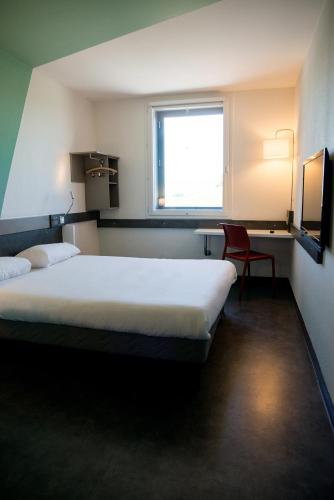 a hotel room with a bed and a window at Ibis Budget Archamps Porte de Genève in Archamps