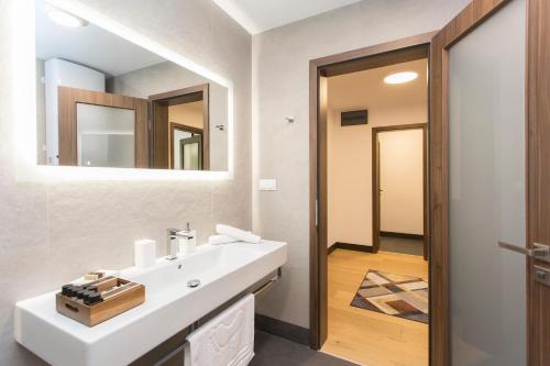 a bathroom with a white sink and a mirror at Complex Gallery Vitosha **** in Sofia