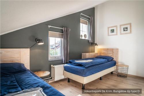 een slaapkamer met 2 bedden met blauwe lakens bij Vakantiepark De Krim Texel in De Cocksdorp