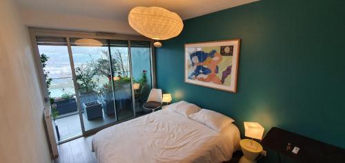 - une chambre avec un lit blanc et un mur vert dans l'établissement Vue sur Seine Musicale, à Boulogne-Billancourt
