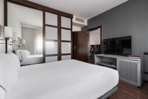 a bedroom with a large white bed and a flat screen tv at Exe Zizur Pamplona in Zizur Mayor