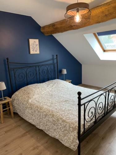 1 dormitorio con cama y pared azul en Gîte « Au petit Bonheur » en Orges