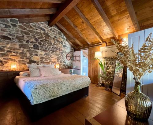 a bedroom with a bed and a stone wall at Apartamentos Rurales El Lleron in Caso