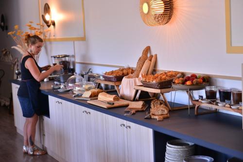 a woman standing in a kitchen with a buffet of food at Logis Hôtel Restaurant Le Chêne Vert in Rocher