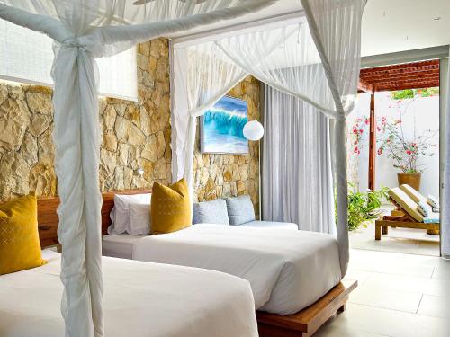 um quarto com 2 camas e uma parede de pedra em Bahia Mar Boutique Hotel em Vilanculos