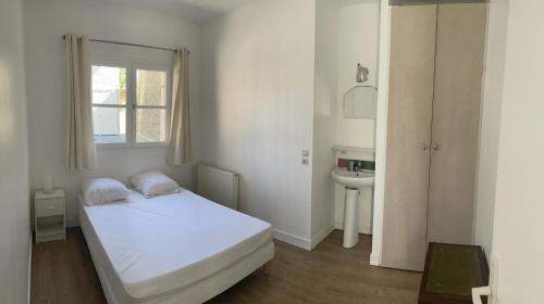 um quarto branco com uma cama e um lavatório em DE LA CROIX em Nanterre