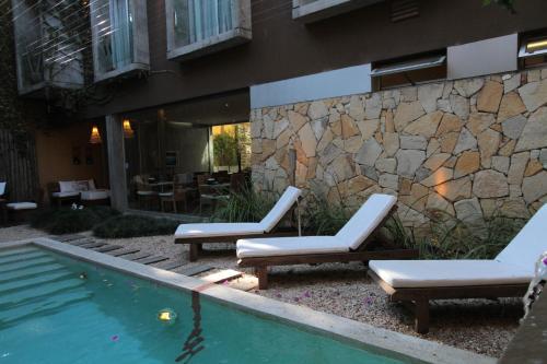 two lounge chairs and a swimming pool in front of a building at Mine Hotel in Buenos Aires
