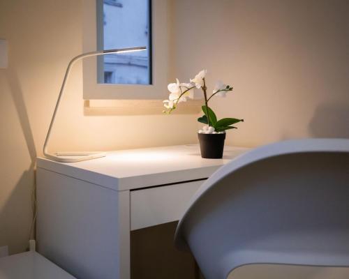 a white desk with a lamp and a flower on it at Essential Rooms in Campobasso