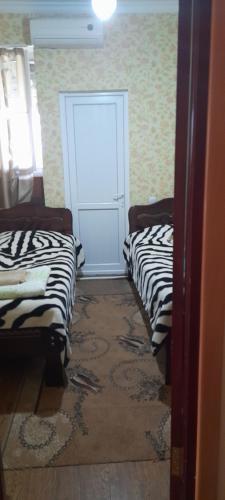a room with two beds and a white door at Nona Guest House in Shilda