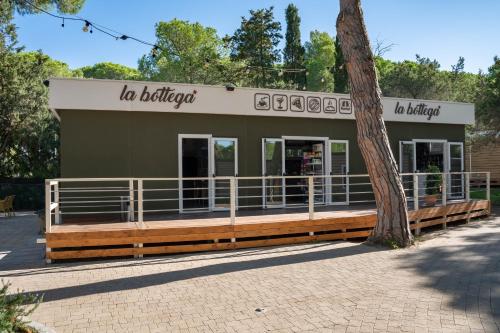 a building with a tree in front of it at Camping Il Capannino Glamping Village in Marina di Bibbona