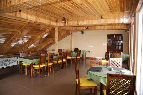 a dining room with tables and chairs and wooden ceilings at Hotel Maenamla Namchi - yagi group in Namchi