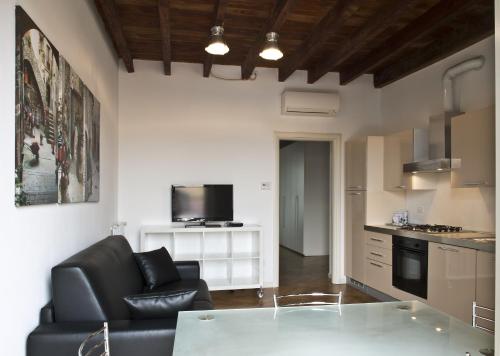 a living room with a black couch and a kitchen at La Maison del Capestrano in Milan
