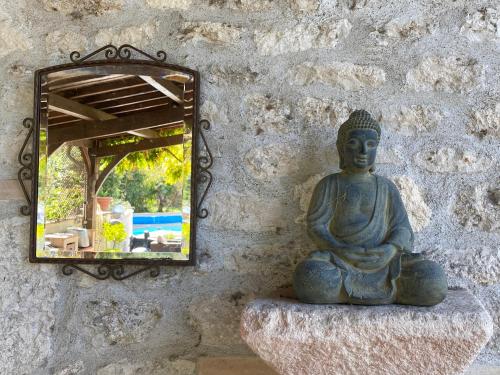 a statue sitting on a stone wall with a mirror at La Caza du quercy in Cazes-Mondenard