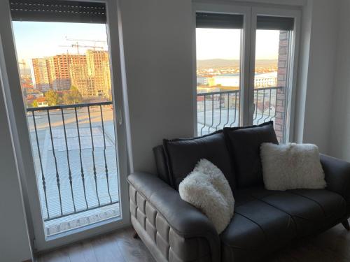 a black couch in a room with a large window at ShooTer Apartments in Ferizaj