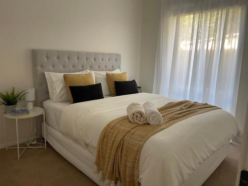 a bedroom with a large white bed with towels on it at Kiama Palms on Terralong in Kiama