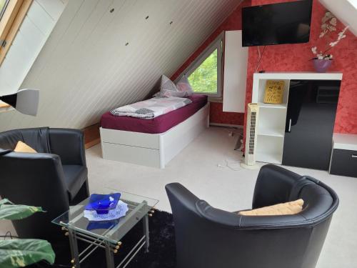 Zimmer im Dachgeschoss mit einem Bett, Stühlen und einem Tisch in der Unterkunft Ferienwohnungen am Krossinsee in Berlin