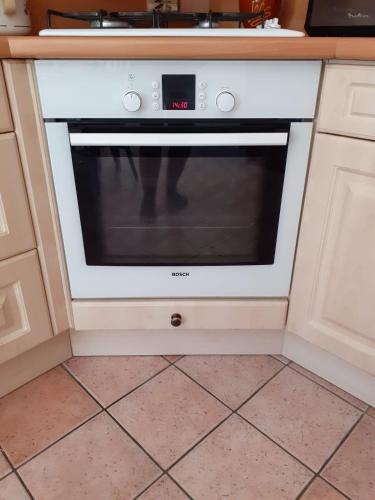 - un four blanc avec une horloge dans la cuisine dans l'établissement Maison du Guier 4 ou 6 personne au coeur du massif, à Saint-Pierre-de-Chartreuse