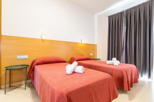two beds in a hotel room with red sheets at Albergue Inturjoven Jaen in Jaén