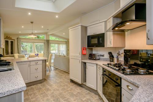 a kitchen with white cabinets and a stove top oven at Woolverstone Marina and Lodge Park in Ipswich