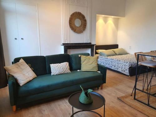 un salon avec un canapé vert et un lit dans l'établissement -Garrigue- Face à la Cité médiévale studio terrasse classé 4☆, à Carcassonne