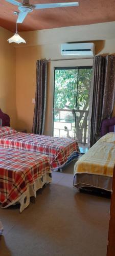 a bedroom with two beds and a large window at Hospedaje San Miguel in Luque