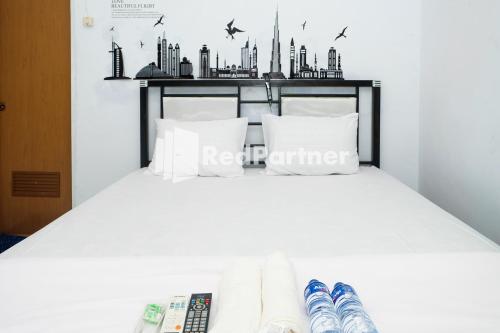 ein Schlafzimmer mit einem weißen Bett und einer Skyline der Stadt an der Wand in der Unterkunft Ninja Room Pasteur Mitra RedDoorz in Bandung