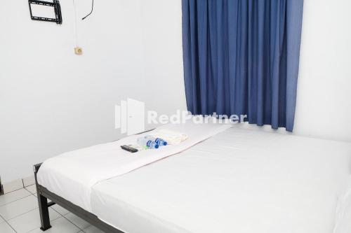 two beds in a room with a blue curtain at Ninja Room Pasteur Mitra RedDoorz in Bandung