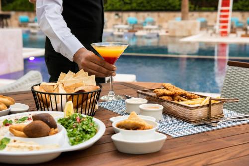 a table with food and a drink on a table with a pool at Swiss-Belsuites Admiral Juffair in Manama