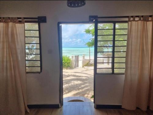 an open door with a view of the beach at Red Monkey Beach Lodge in Jambiani