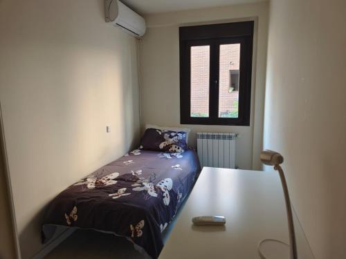 a small bedroom with a bed and a table at Casa Jaime in Alcalá de Henares