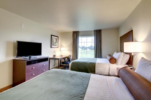 a hotel room with two beds and a flat screen tv at Cobblestone Inn & Suites - Schuyler in Schuyler