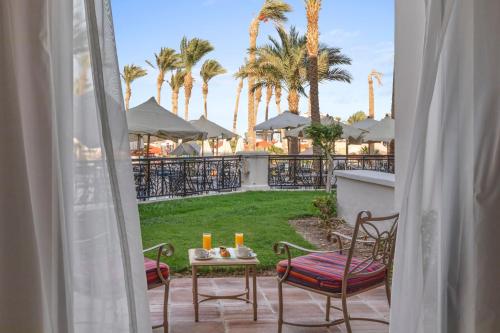 a patio with a table and chairs and palm trees at Pickalbatros The Palace Port Ghalib in Port Ghalib