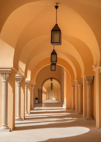 an arcade of a building with columns and lights at Royal Tulip Korbous Bay Thalasso & Springs in Qurbuş