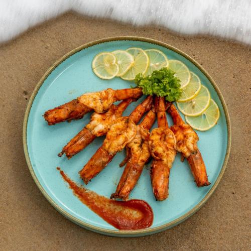 a blue plate of food with shrimp and lemon slices at C Roque Beach Resort in Colva