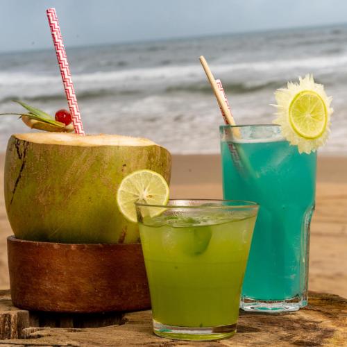 a table with two drinks on the beach at C Roque Beach Resort in Colva