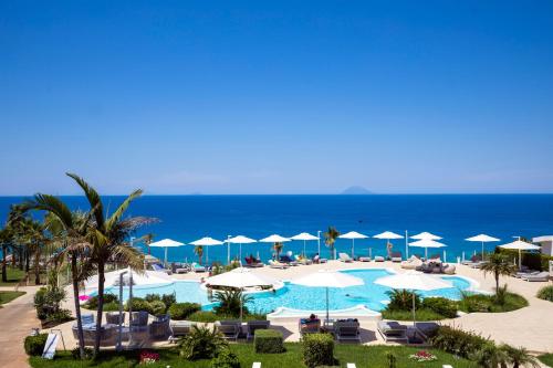 Blick auf einen Pool mit Sonnenschirmen und das Meer in der Unterkunft Borgo Donna Canfora in Capo Vaticano