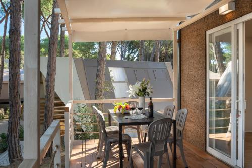a patio with a table and chairs on a balcony at Camping Il Capannino Glamping Village in Marina di Bibbona