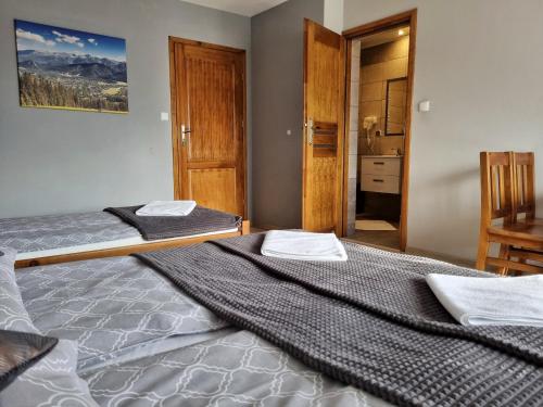 a bedroom with two beds and a bathroom at Pokoje u Hani - sauna, balia z hydromasażem in Bukowina Tatrzańska
