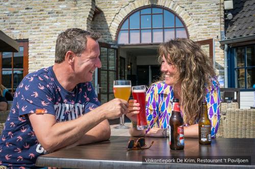 a man and woman sitting at a table with glasses of beer at Vakantiepark De Krim Texel in De Cocksdorp