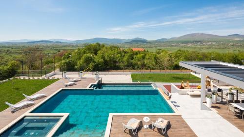 einen Pool mit Blick auf ein Haus in der Unterkunft Luxury Villa Arya with 77sqm heated pool, hot-tub, sauna, gym, billiard, playgrounds, 6 bedroom in Bajagić