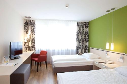 a hotel room with two beds and a desk and a tv at Hotel Schwanen Stuttgart Airport/Messe in Filderstadt