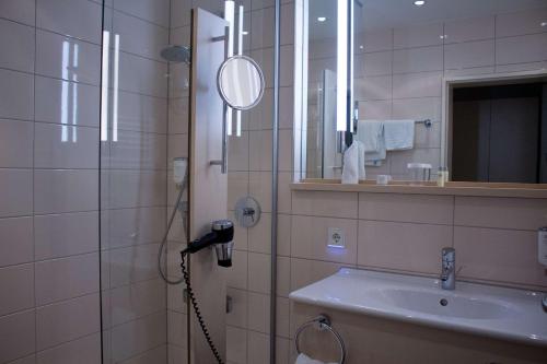 a bathroom with a shower with a sink and a mirror at Hotel Schwanen Stuttgart Airport/Messe in Filderstadt